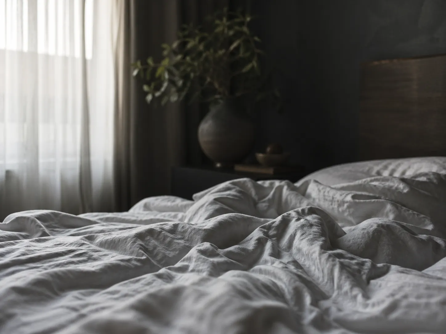 Crumpled linen sheets in a dark moody bedroom